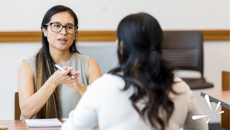 Leadership feedback conversation between two colleagues discussing IDI assessment results in an office setting